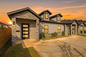 A residential building with a stone facade, multiple garage doors, and a driveway. - The NRG City Retreat (Houston)