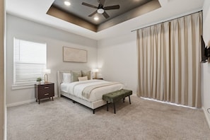A bedroom with a bed, bedside tables, a ceiling fan, a window with blinds, and a curtain. - The NRG City Retreat (Houston)