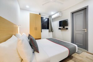 Een hotelkamer met een bed, een kledingkast, een televisie en een deur.