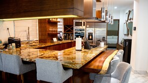 A modern kitchen with a marble countertop, stainless steel appliances, and a bar area with seating. - The Five Apartments by Monyxbnb (Puerto Vallarta)