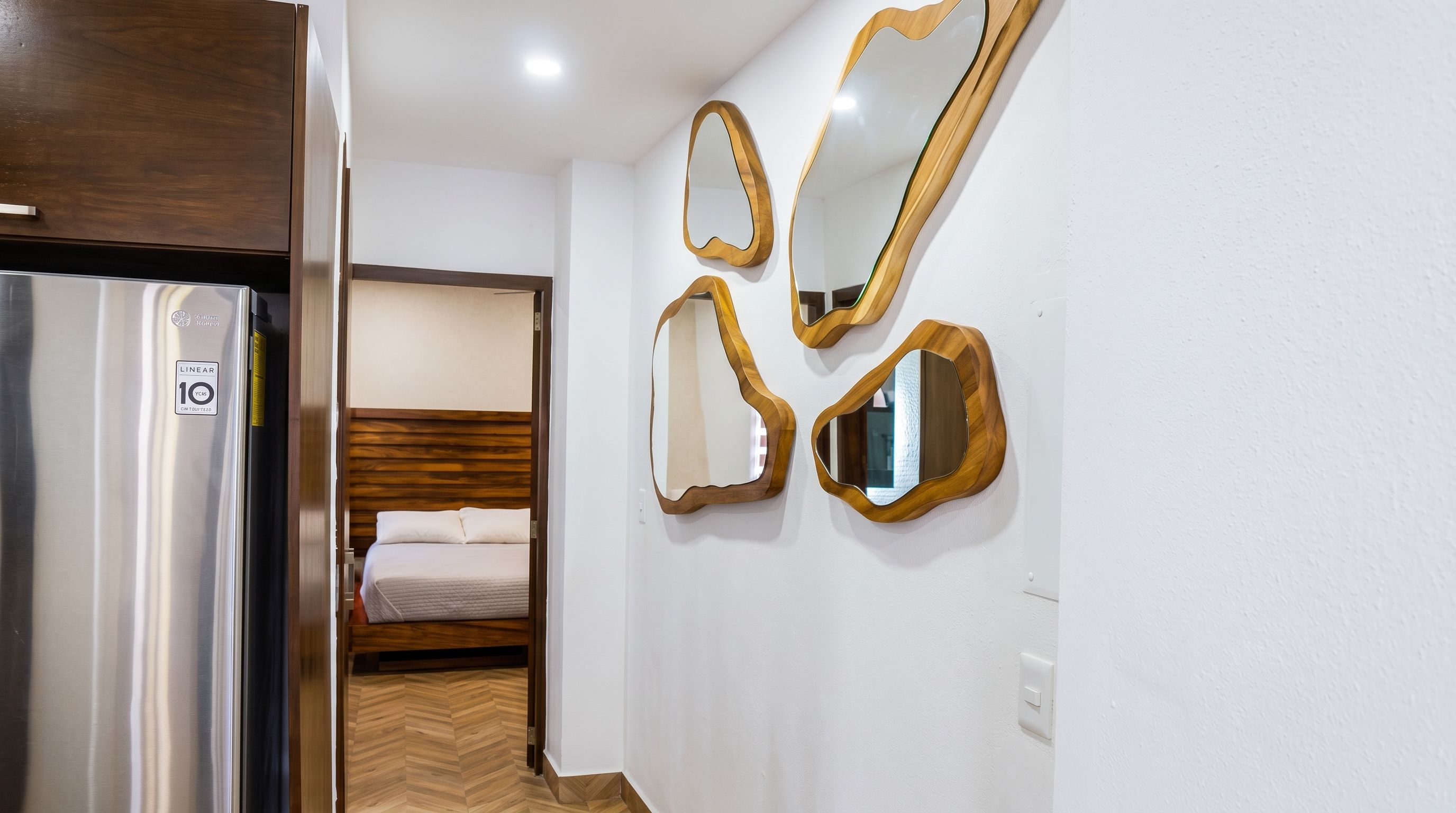 Quarto de hotel com cama, guarda-roupa e espelho fixado na parede.