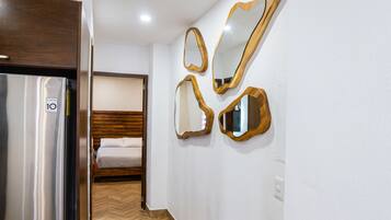 Quarto de hotel com cama, guarda-roupa e espelho fixado na parede.