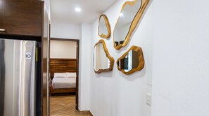 Quarto de hotel com cama, guarda-roupa e espelho fixado na parede.