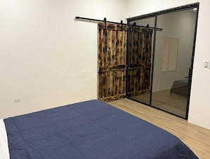 A bedroom with a bed, a sliding door, and a mirror. - Luxury Modern Ranch, Private Pool & Farm Animals (santa cruz)