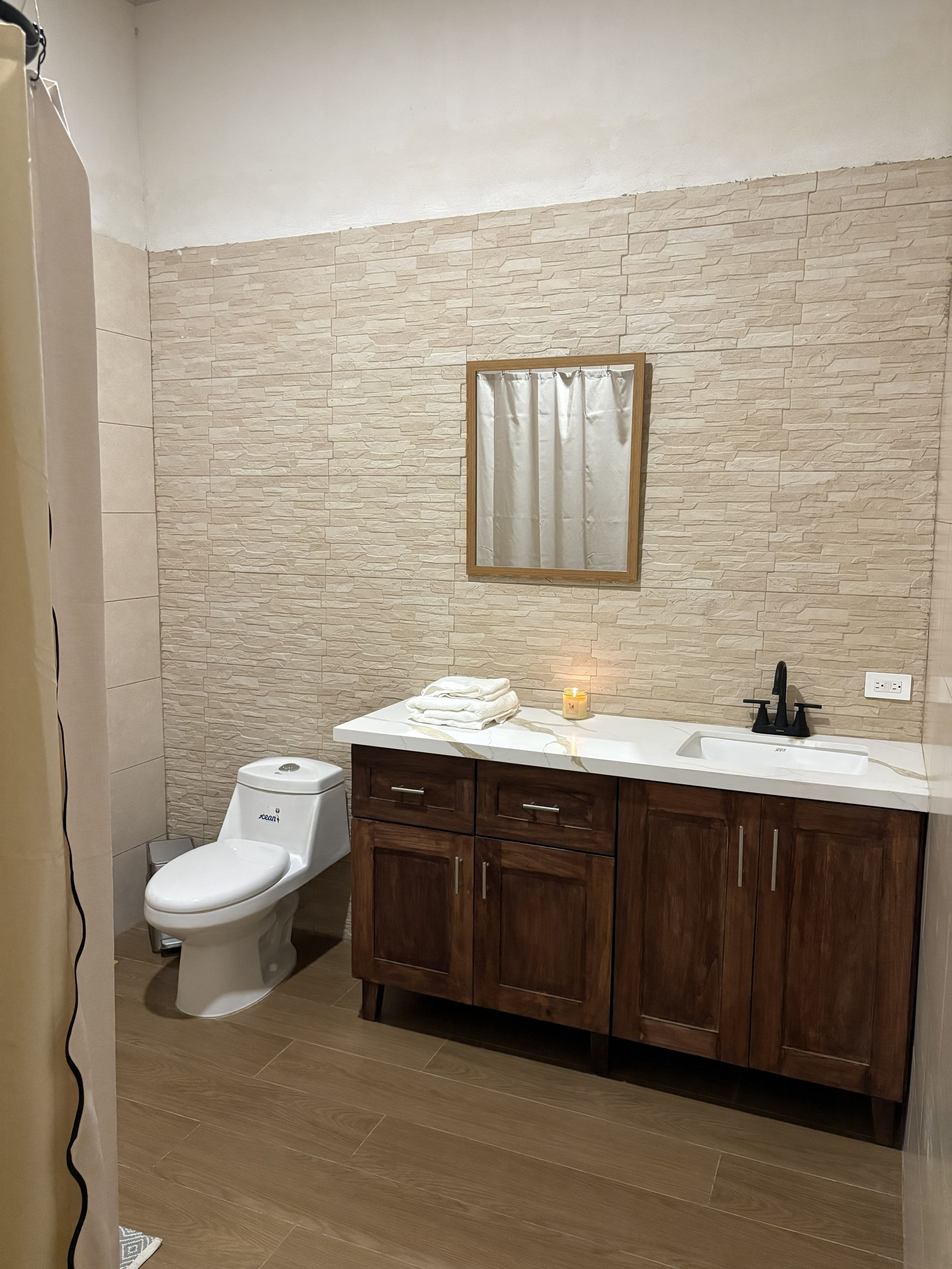 A bathroom with a toilet, a sink, and a mirror.