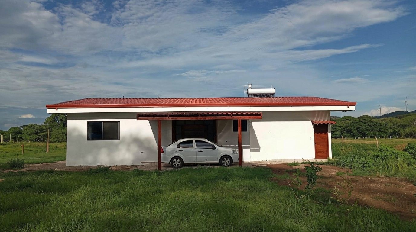 Um edifício térreo com telhado vermelho, um carro estacionado em frente e um campo gramado ao fundo.