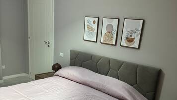 Une chambre à coucher avec un lit, une porte et trois œuvres d’art accrochées au mur.