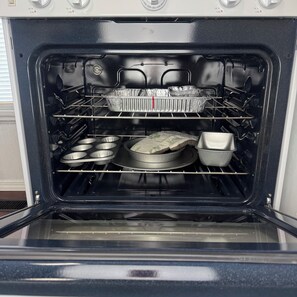 An open oven with various baking trays and pans inside.