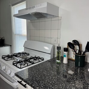 Een keuken met een gasfornuis, een afzuigkap en een granieten aanrecht.