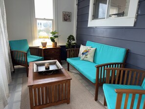 A living room with a sofa, two chairs, a wooden coffee table, a lamp, and a window.