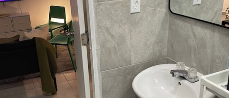 A bathroom with a white sink, a mirror, and a green chair.
