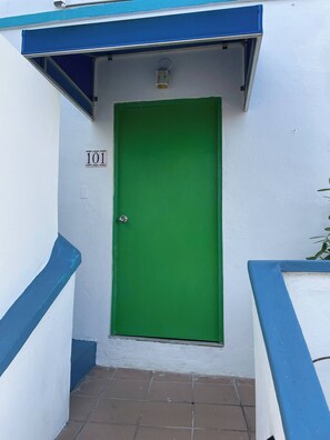 A green door with a number sign, a blue awning, and a tiled floor. - Apartment, 2B, AC, Pool 10 Minutes Airport (San Juan)