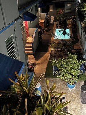 A courtyard with a swimming pool, potted plants, and outdoor furniture. - Apartment, 2B, AC, Pool 10 Minutes Airport (San Juan)