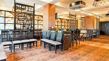 A spacious indoor area with wooden flooring, multiple seating arrangements, and a modern design with geometric patterns on the walls.