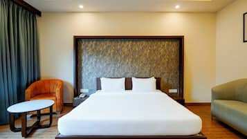 Habitación de hotel con una cama grande, una mesita de noche con teléfono, una silla y un sofá.