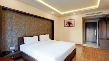 A hotel room with a large bed, a wooden nightstand, a telephone, and a wall-mounted artwork.