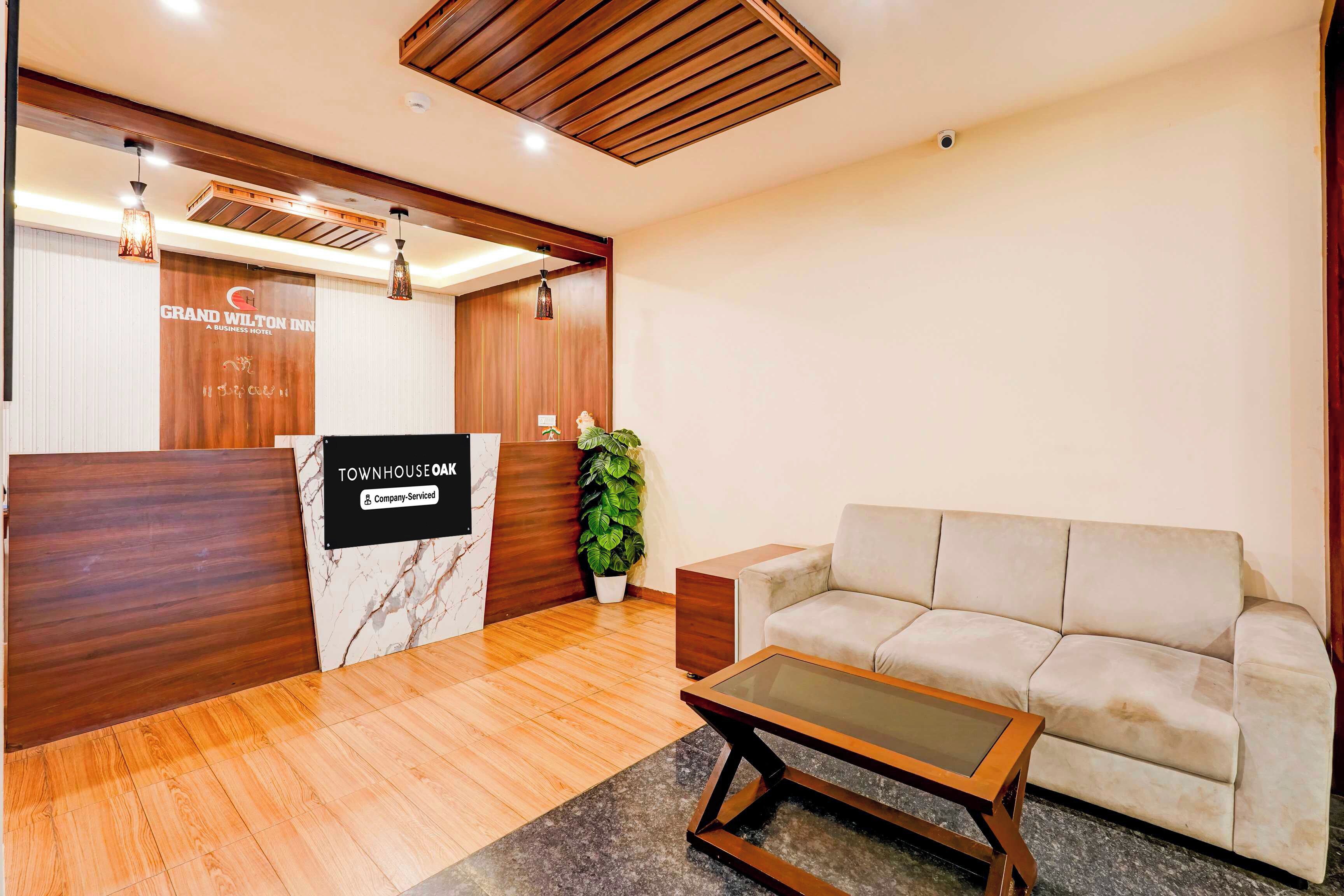 A reception area with a wooden reception desk, a sofa, a coffee table, and a potted plant.