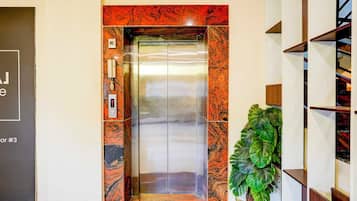 An elevator with a marble facade, a phone, and a digital display.