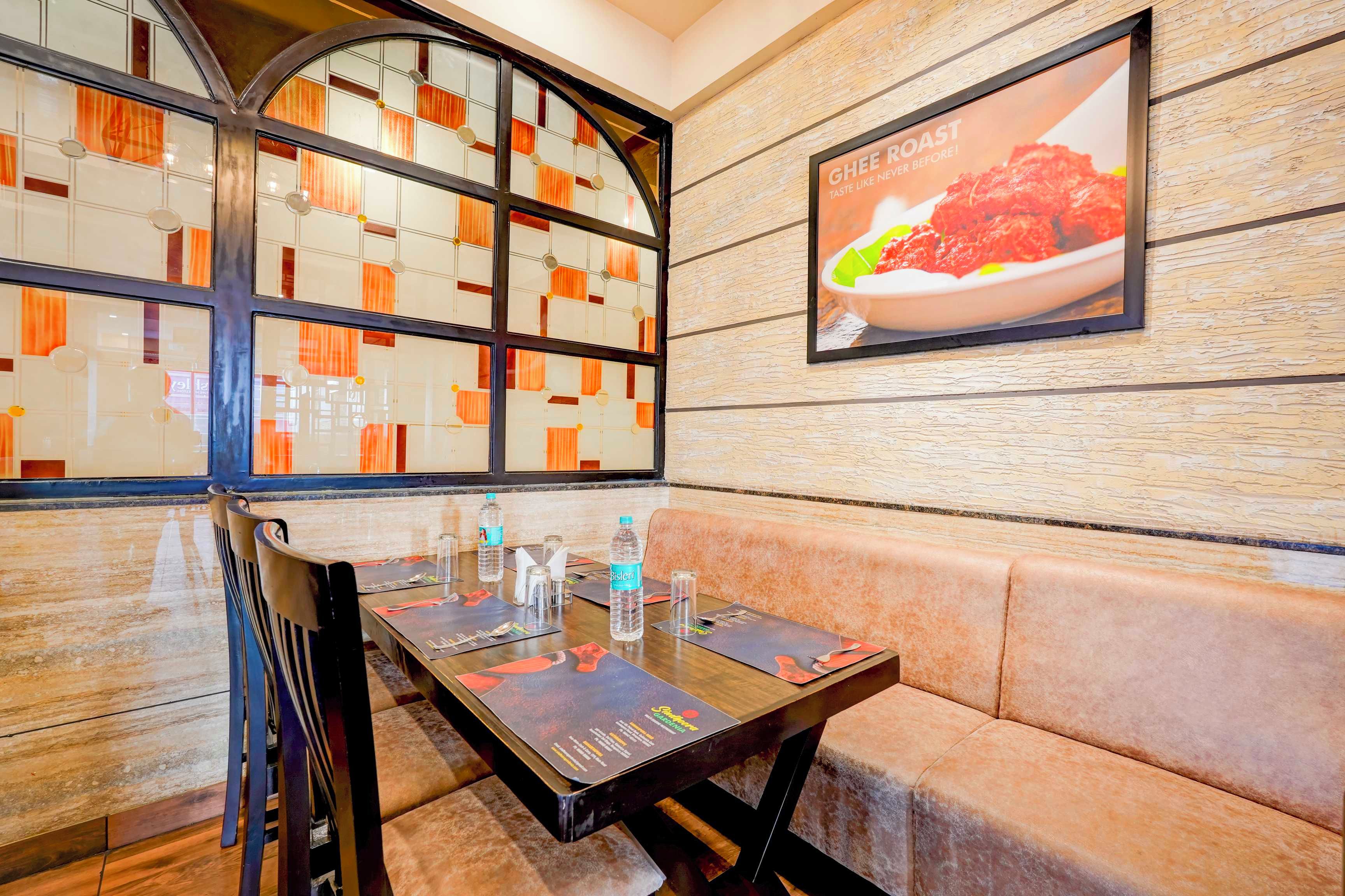 Ein Restaurantinneres mit einer Sitzecke mit Boxen, einem Tisch mit Wasserflaschen und einer Speisekarte.