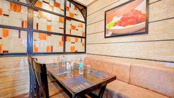 A restaurant interior with a booth seating area, a table set with water bottles, and a menu.