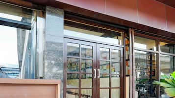A modern building entrance with large glass doors and windows, a concrete pillar, and a metal awning.