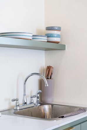 A kitchen with a stainless steel sink, a faucet, and a shelf holding plates and bowls. -  Casa Norma in Mayagüez (Mayagüez)