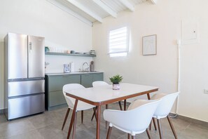 A compact kitchen with a built-in refrigerator, a dining table with four chairs, and a small potted plant on the table. -  Casa Norma in Mayagüez (Mayagüez)
