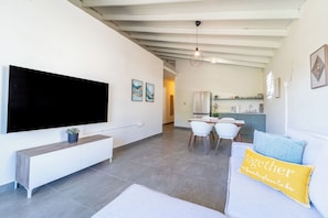 A modern living room with a flat-screen TV, a dining area with chairs, and a kitchen in the background. -  Casa Norma in Mayagüez (Mayagüez)