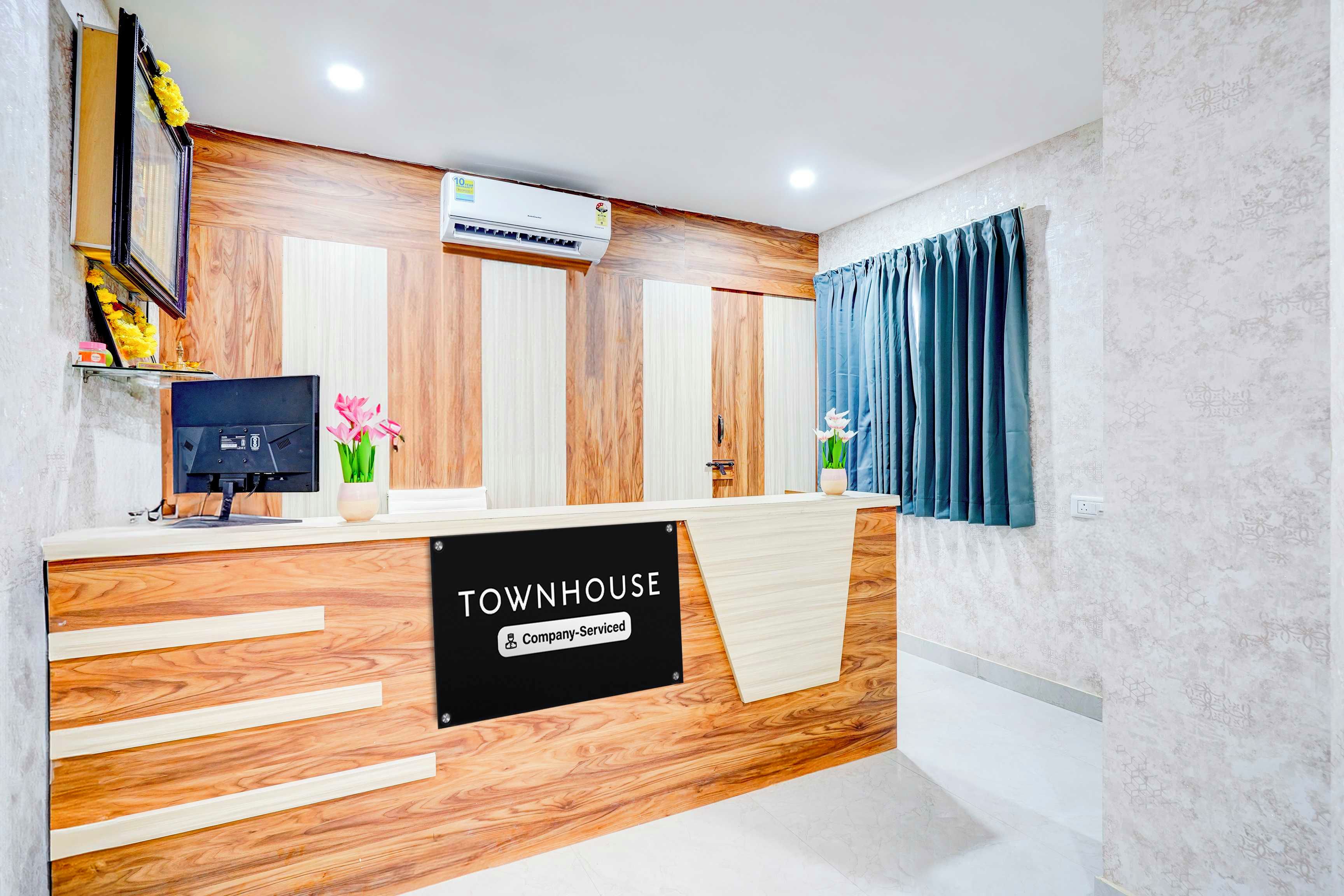 A reception desk with a 'TOWNHOUSE' sign, a computer monitor, and a potted plant.