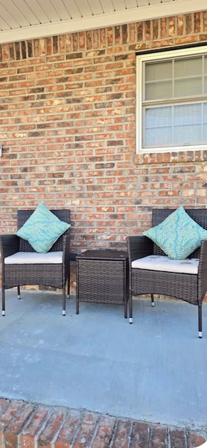 Two wicker chairs with cushions against a brick wall, a window above, and a concrete floor. - Cozy Haven of Florence
2-bedroom 2.5 bath  
 (Florence)