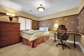 Ein Schlafzimmer mit Bett, Kommode, Schreibtisch, Stuhl und einer Deckenleuchte.