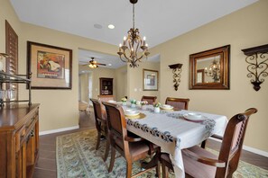 A dining room with a chandelier, wooden chairs, a table set for four, and a patterned rug. - Game loft retreat & patio near the Strip 5BR (Las Vegas)