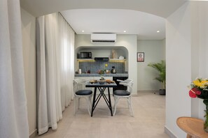 Eine moderne Küche mit Essbereich, ausgestattet mit einem Tisch, Stühlen, einer Kaffeemaschine und einem kleinen Kühlschrank.