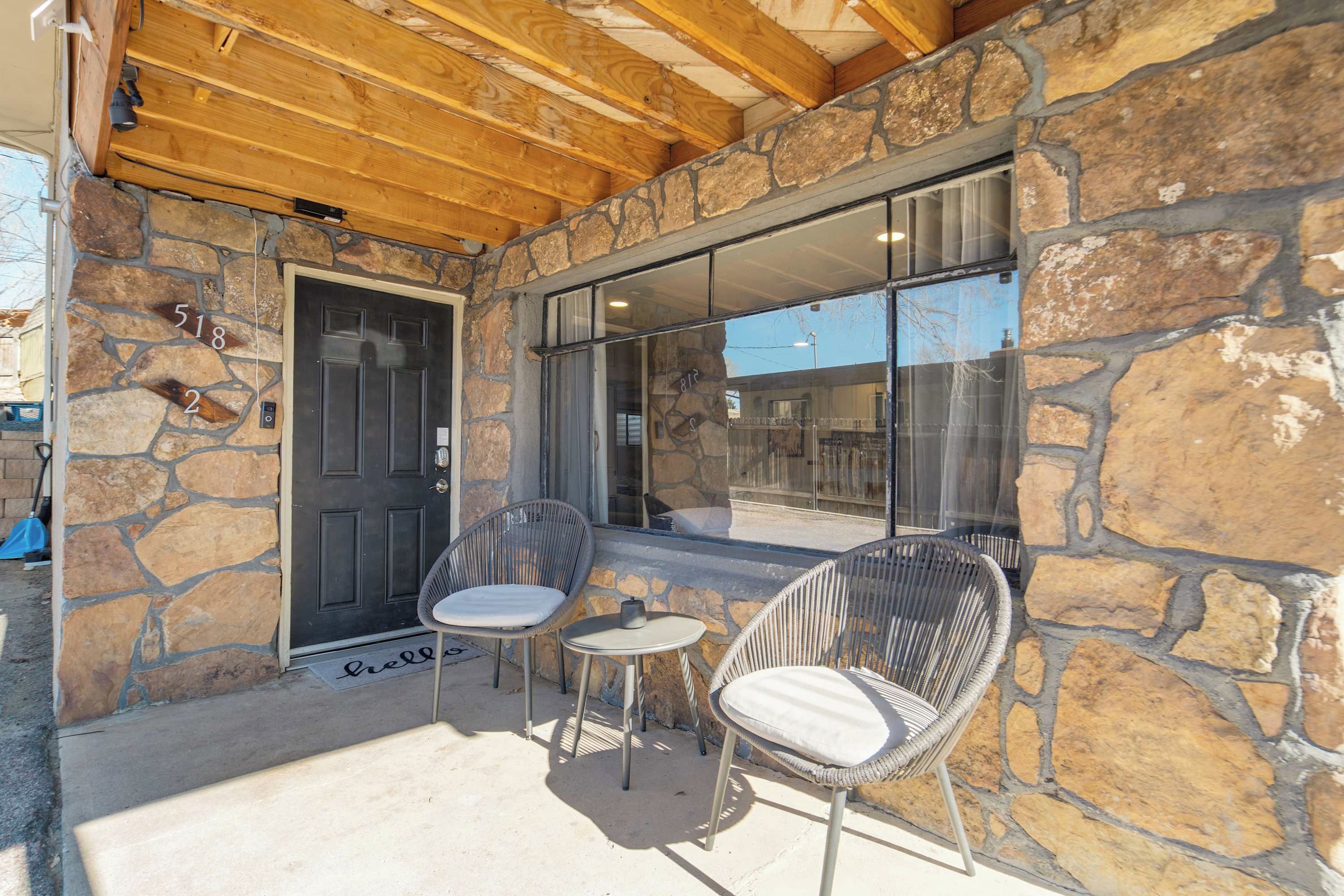 A stone exterior with a wooden ceiling, two wicker chairs, and a small table.