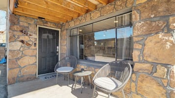 A stone exterior with a wooden ceiling, two wicker chairs, and a small table.
