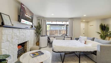 A modern living room with a fireplace, a flat-screen TV, a sofa, a coffee table, and a view of the outside.