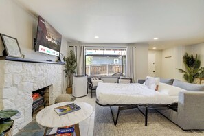 Uma sala de estar moderna com lareira, televisão de tela plana, sofá, mesa de centro e vista para o exterior.