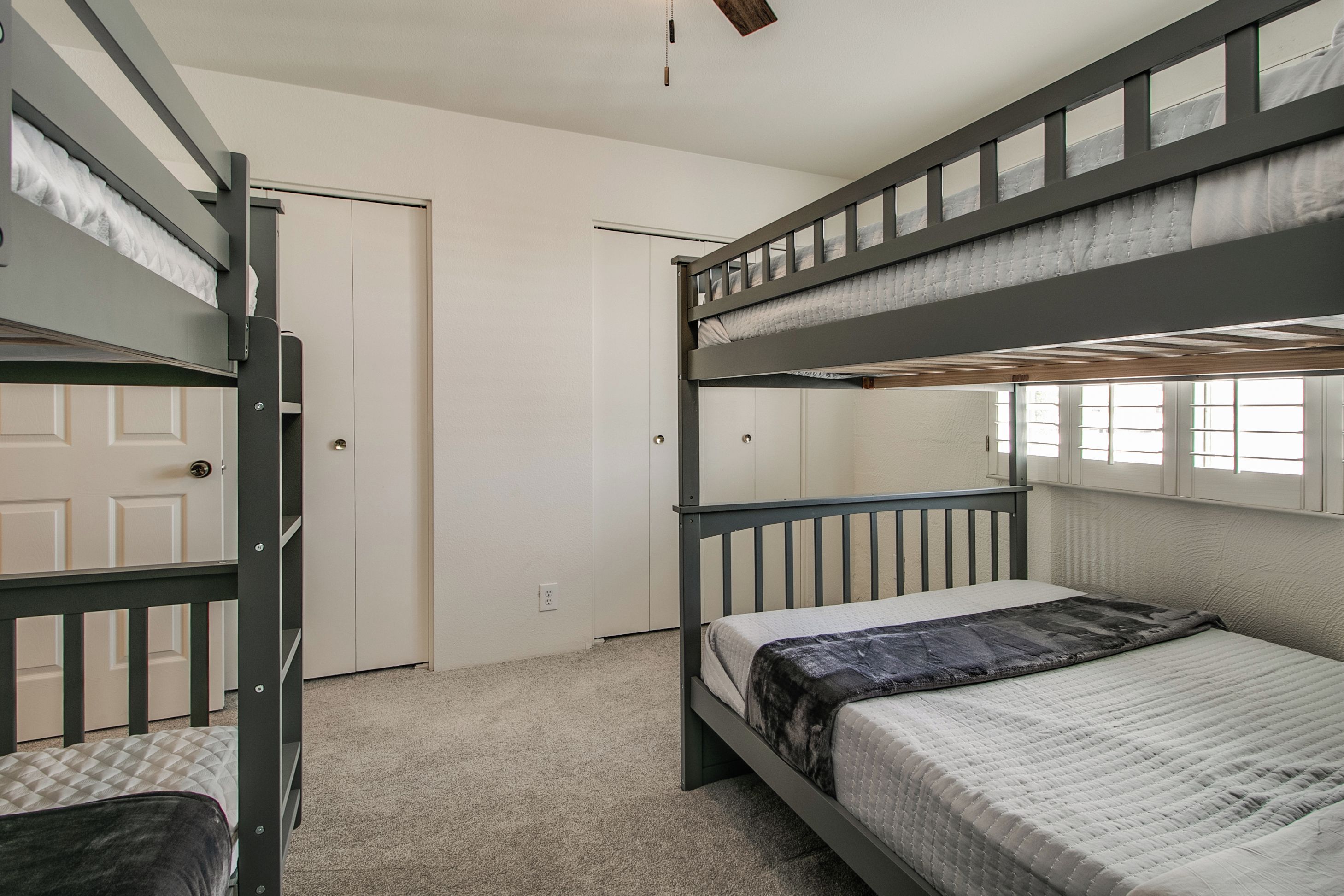 A bunk bed room with a door and a window.