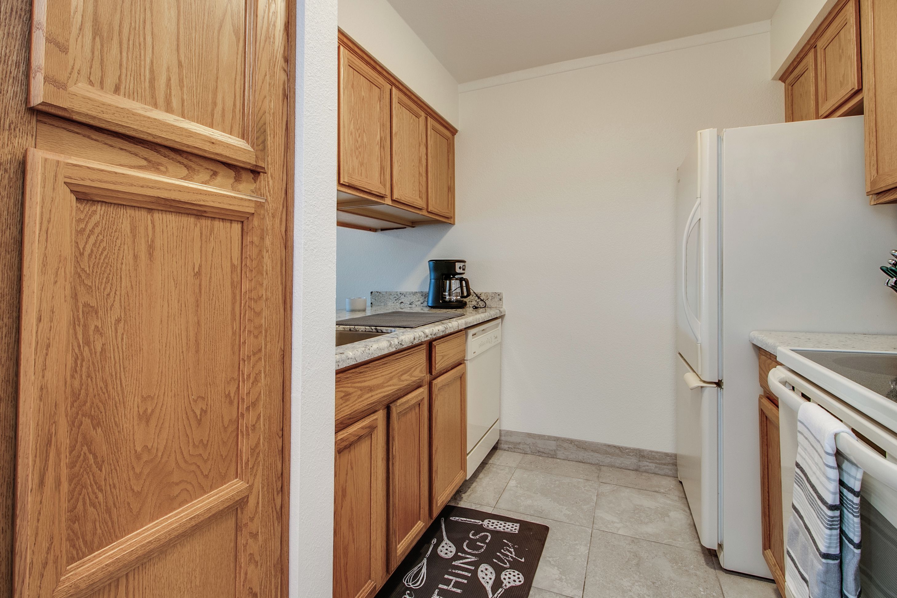 A kitchen with wooden cabinets, a coffee maker, a refrigerator, and a dishwasher.