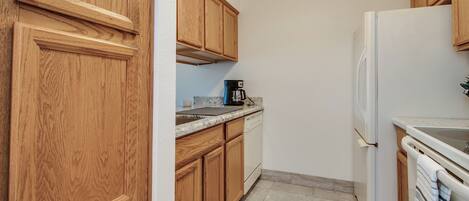 A kitchen with wooden cabinets, a coffee maker, a refrigerator, and a dishwasher.