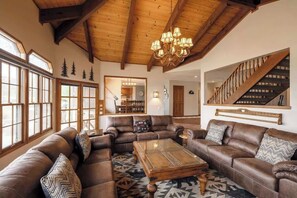 Ein großzügiges Wohnzimmer mit Ledersofas, einem Holztisch und einer Kristallleuchtre.