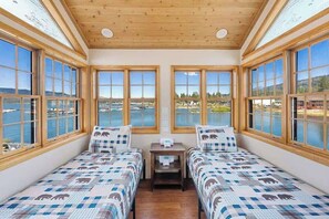 A room with two beds, large windows, and a view of a body of water. - Big Bear Lakefront | Dock, Hot Tub & Game Room (Big Bear Lake)