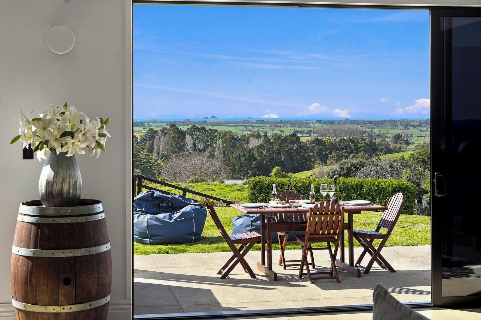 Un comedor con una mesa y sillas, un florero con flores y vistas a un paisaje a través de un ventanal.