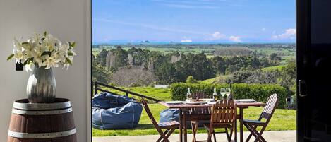 Un comedor con una mesa y sillas, un florero con flores y vistas a un paisaje a través de un ventanal.