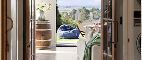A room with a view of a landscape, a wooden barrel, a vase with flowers, and a bean bag chair.
