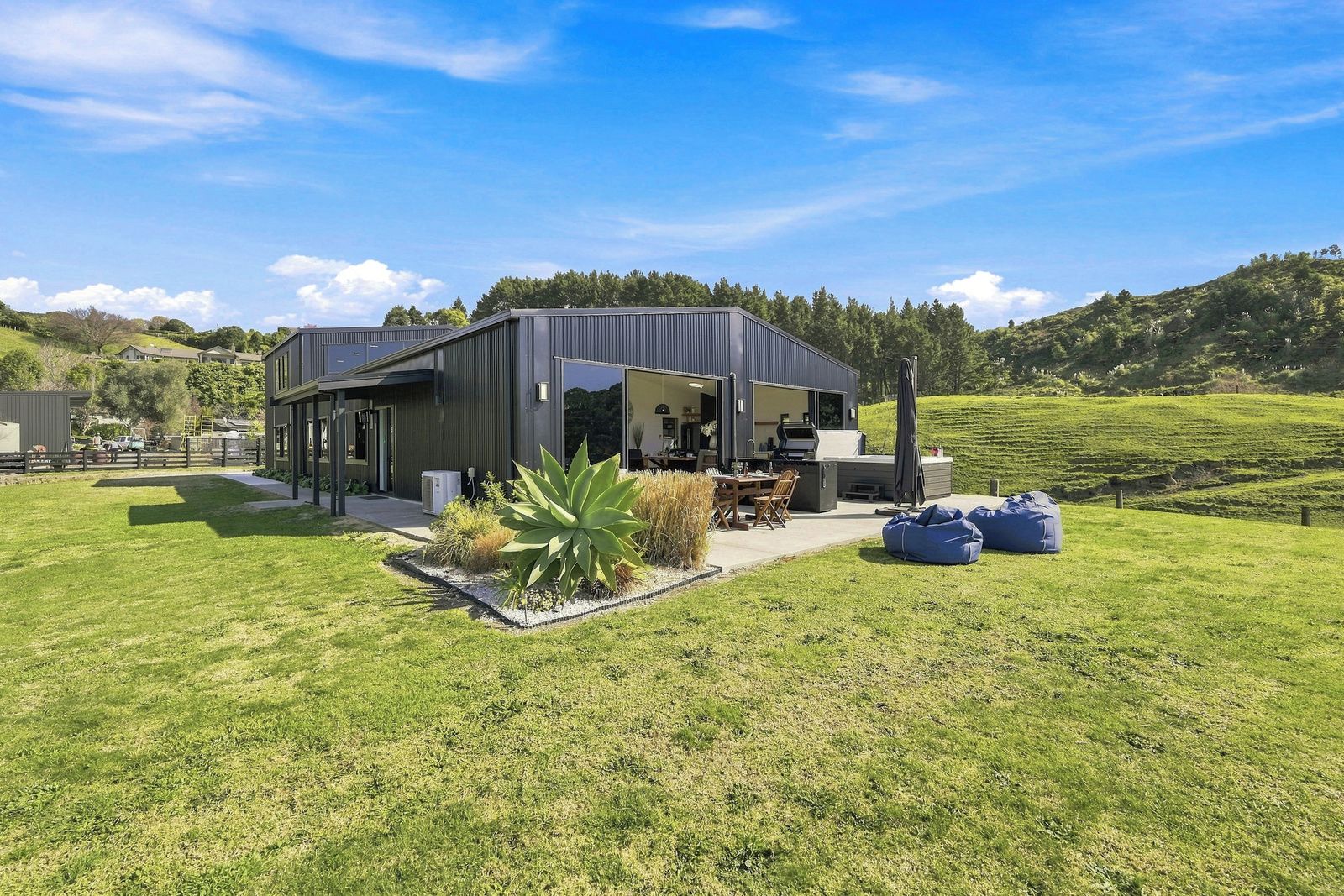 Una casa moderna con un patio, mobiliario exterior y una planta grande.