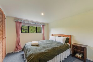 A bedroom with a single bed, a nightstand, a window with curtains, and a ceiling light.