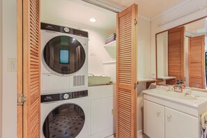 A compact laundry room with a washing machine, dryer, and a small sink with a mirror.