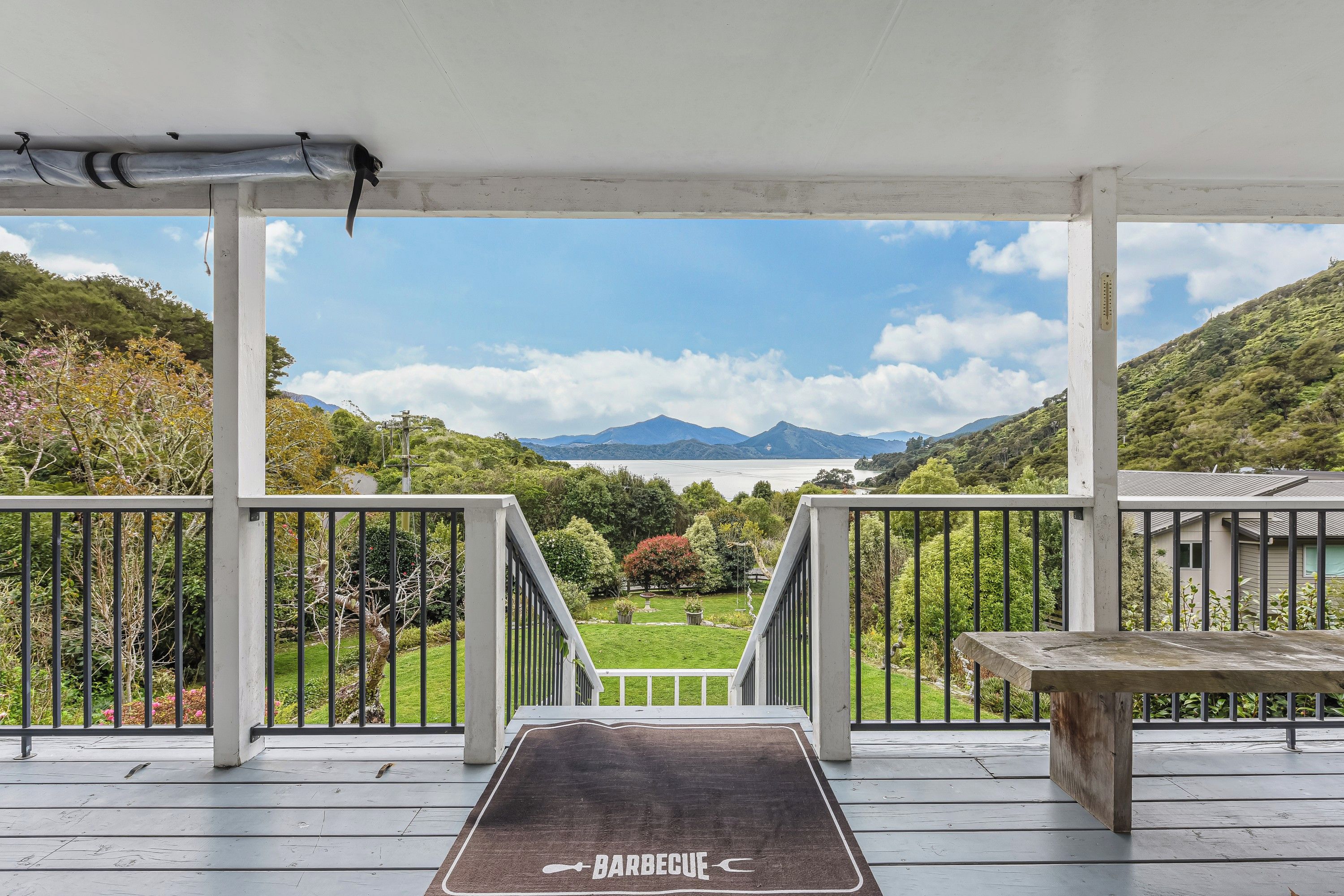 A covered outdoor area with a view of a lake and mountains.