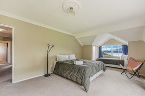 Une chambre avec deux lits, une lampe sur pied et une vue sur l’extérieur.